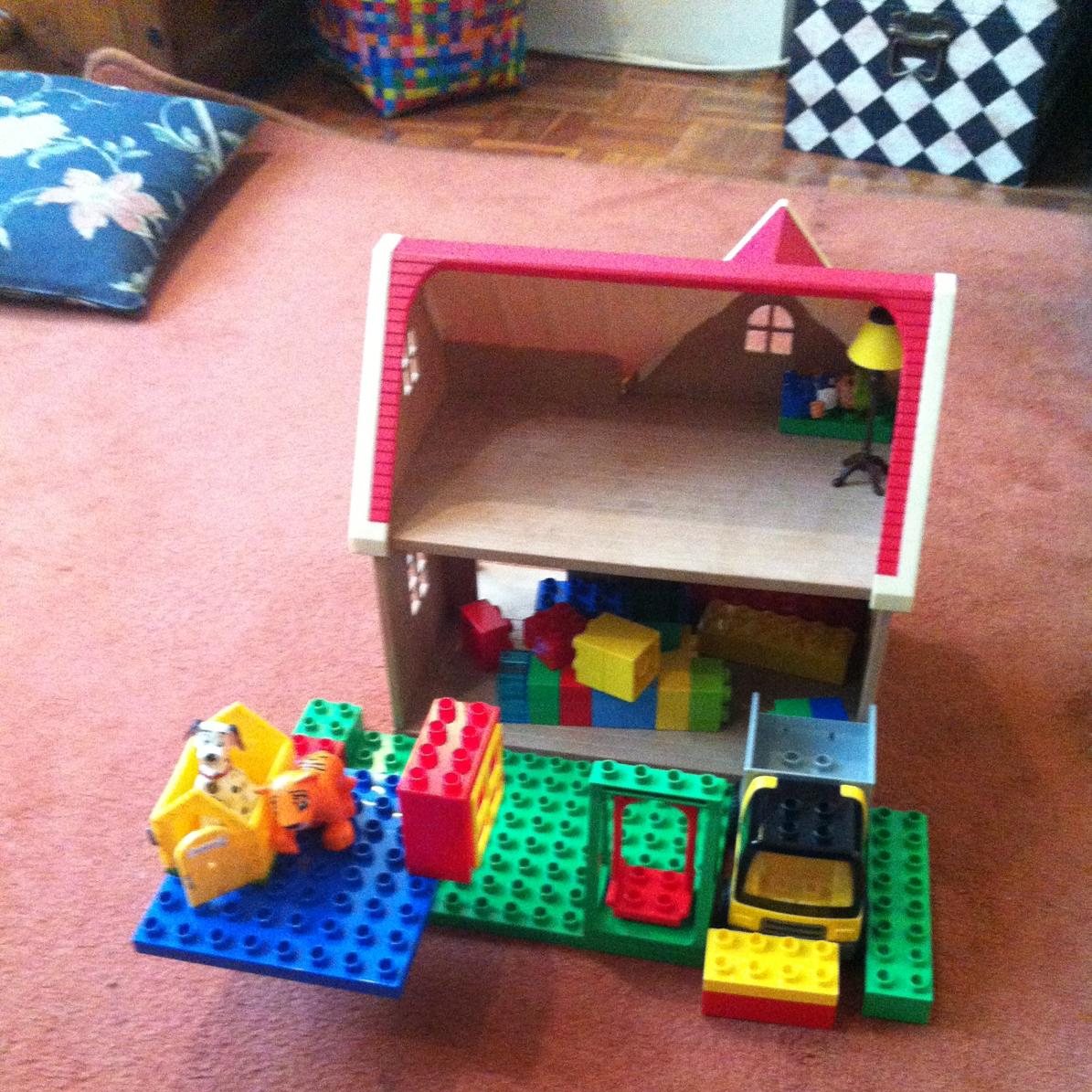 Construcción con bloques y casa de juguete en una escena de juego infantil.